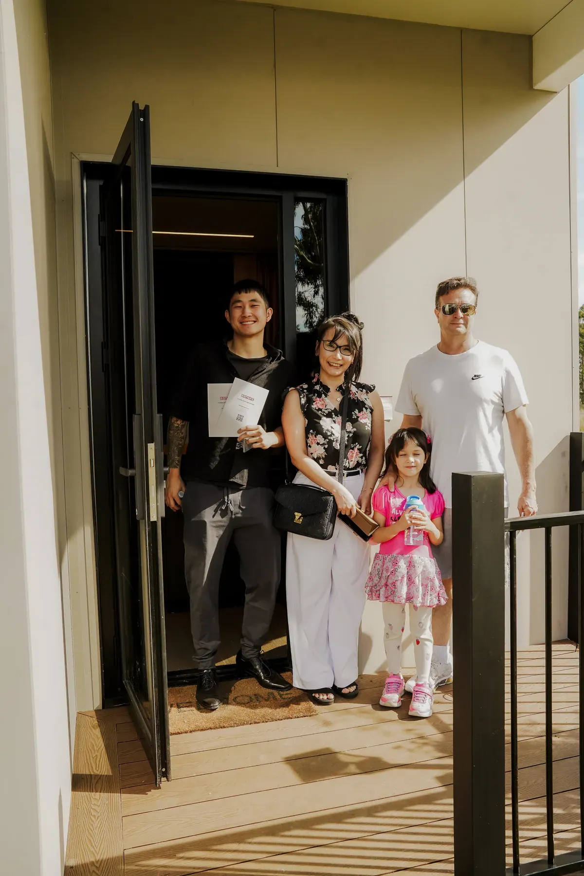 A family standing at the open front door of the display home.