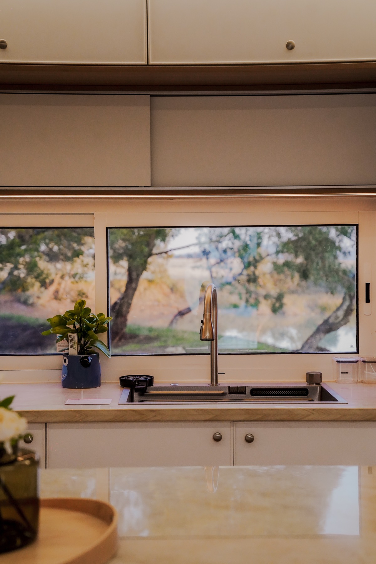 The Bonsai one-bedroom kitchen sink with trees visible through the window.